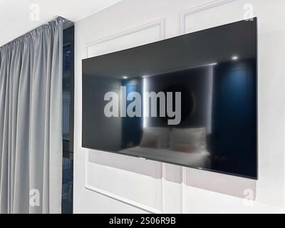 Grand téléviseur moderne sur le mur blanc dans la chambre Banque D'Images