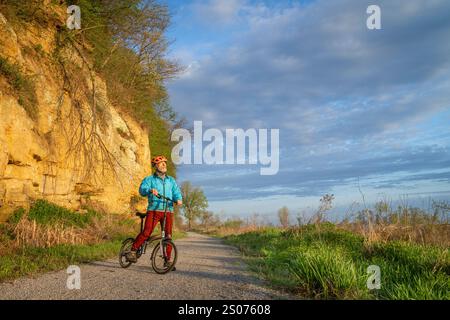 Cycliste masculin senior chevauchant un vélo pliant sur Steamboat trace, piste cyclable convertie à partir d'un chemin de fer abandonné, près du Pérou, Nebraska, matin de printemps Banque D'Images