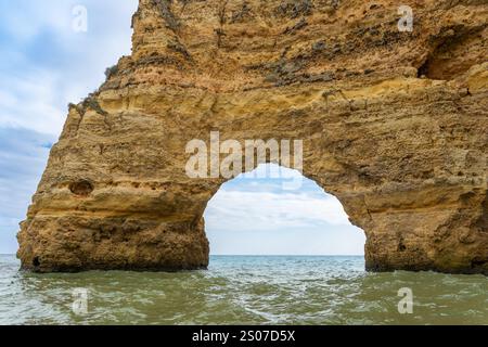 Falaises côtières époustouflantes avec des grottes marines complexes, présentant des couches de formations rocheuses dorées et rougeâtres. Les eaux turquoises ajoutent au souffle Banque D'Images