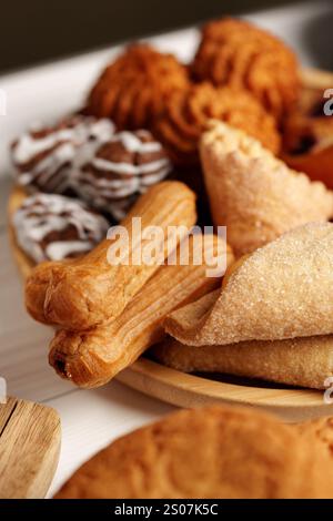 Assortiment de pâtisseries traditionnelles présentées sur une assiette en bois lors d'un rassemblement festif Banque D'Images