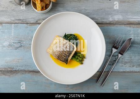 Filet de bar grillé servi avec des garnitures dans un restaurant gastronomique Banque D'Images