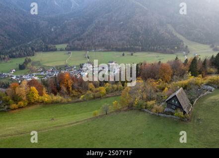 Drone vue aérienne d'un village pittoresque et d'une cabane en bois solitaire nichée au milieu du feuillage d'automne vibrant des alpes Banque D'Images