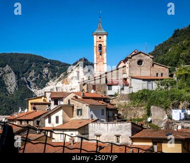 Une vue pittoresque d'un petit village italien à l'architecture traditionnelle, avec une grande tour de l'horloge et des montagnes en arrière-plan. Banque D'Images