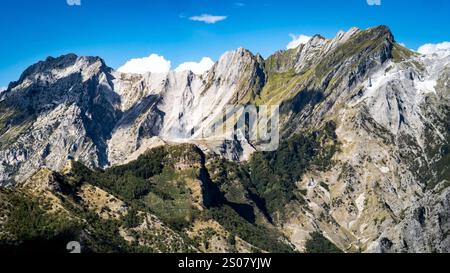 Une vue imprenable sur les montagnes escarpées sous un ciel bleu clair, présentant des falaises abruptes et des pics rocheux avec des taches de verdure à la base. Banque D'Images