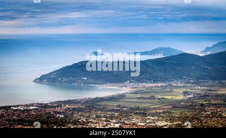 Vue aérienne d'un paysage côtier avec des montagnes, une plage et des îles au loin sous un ciel nuageux. Banque D'Images