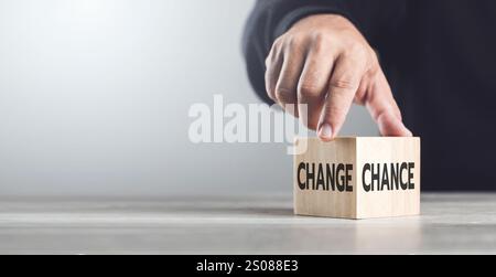 Un homme choisit entre les mots «CHANGEMENT» et «CHANCE» sur des blocs de bois, symbolisant le processus de prise de décision et embrassant les opportunités de croissance Banque D'Images