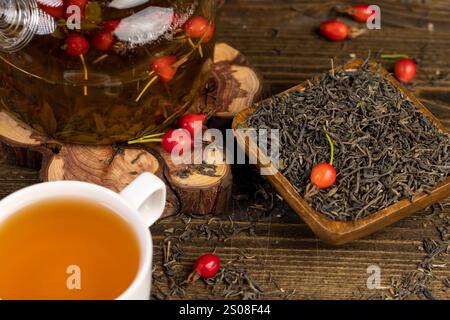 délicieux thé avec l'ajout de fruits roses, fruits de rose dans le thé rouge et vert sur la table pendant la cuisson Banque D'Images
