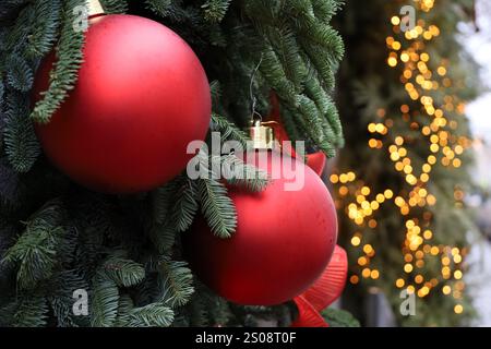 Célébration du nouvel an dans la ville d'hiver, branches d'arbre de Noël avec des boules rouges sur fond de lumières dorées Banque D'Images