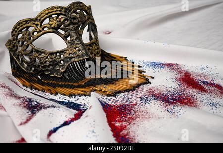 Élégant masque vénitien avec des perles couchées sur un tissu blanc avec des paillettes rouges, blanches et bleues, parfait pour célébrer le carnaval ou toute occasion spéciale. Banque D'Images