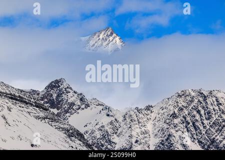 joli paysage de montagnes rocheuses couvertes de neige partielle surmontées de nuages mais au-dessus des nuages est un sommet plus élevé dans une tache de ciel bleu sur le sud de la géorgie Banque D'Images