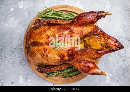 Canard entier cuit au four avec des pommes sur planche de bois. fond gris. vue de dessus. Banque D'Images