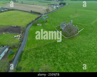 Un grand champ avec une route qui le traverse et un château au milieu. Le château est entouré d'une clôture et il est abandonné. vue de dessus à partir d'un dist Banque D'Images