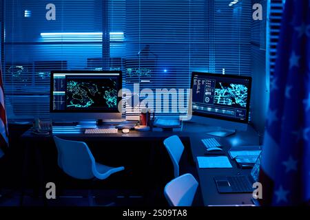 Drapeaux des États-Unis entourant les lieux de travail des officiers du centre de commandement militaire avec des ordinateurs de bureau avec des données graphiques sur les écrans Banque D'Images