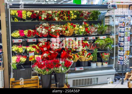 Affichage de bouquets de fleurs colorés disposés dans le réfrigérateur du magasin avec étiquettes de prix et cartes de voeux à proximité. Banque D'Images