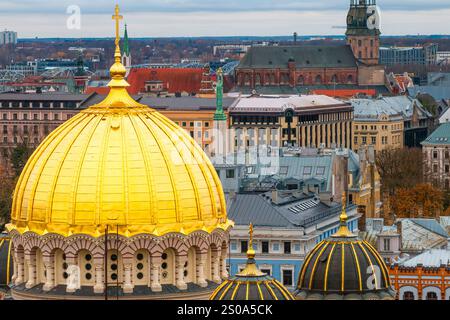 Le dôme doré de la cathédrale de la Nativité du Christ se distingue dans l'horizon de Riga, avec la flèche de l'église de Pierre visible sous un ciel couvert. Banque D'Images