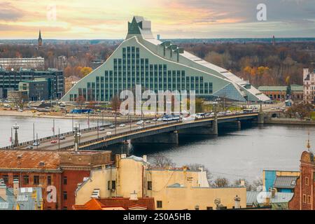 La Bibliothèque nationale de Lettonie, avec sa conception en verre et en acier, se trouve près de la rivière Daugava. Un pont et des arbres automnaux sont visibles sous un overc Banque D'Images
