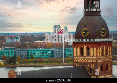 L'image capture une vue aérienne de Riga, Lettonie, mettant en évidence la cathédrale de Riga avec sa tour de l'horloge. Les bâtiments modernes et la rivière Daugava sont vi Banque D'Images
