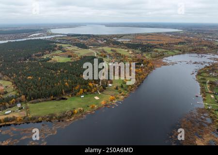 Une perspective aérienne d'une zone rurale avec des forêts, des champs ouverts et une voie navigable sinueuse. Les arbres automnaux contrastent avec l'eau sombre, avec un dist Banque D'Images
