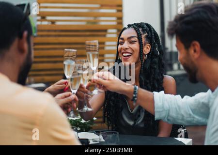 Une femme souriante grillant avec des amis lors d'un élégant rassemblement en plein air, rayonnant de joie et célébrant un moment festif. Banque D'Images