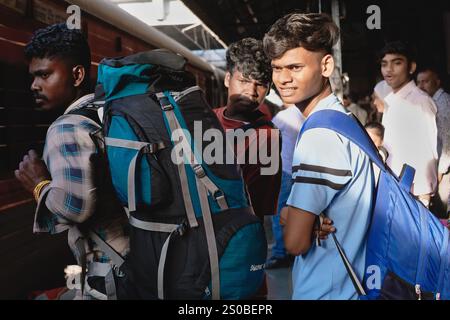 Deux jeunes indiens transportant des sacs à dos sur un quai de la gare de Dadar à Mumbai, en Inde, attendant de monter à bord de leur train longue distance Banque D'Images