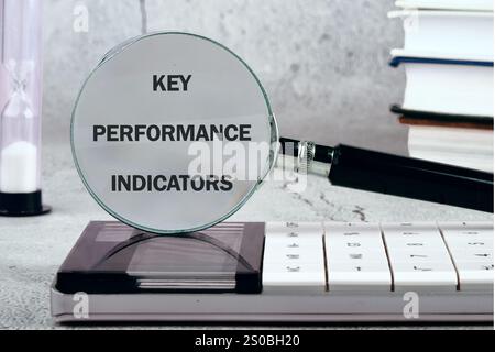 Concept commercial et financier. Mots KPI (Key performance Indicator) écrits à l'aide d'une loupe, vue de face. Banque D'Images