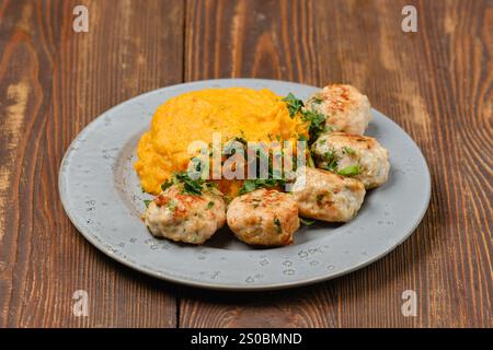 Boulettes de viande juteuses à base de viande hachée avec un monticule de purée de citrouille lisse et crémeuse, garnie d'herbes fraîches Banque D'Images