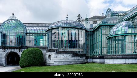 Une magnifique serre à l'architecture de verre complexe, avec des toits en dôme et une base en pierre. Entouré d'une végétation luxuriante et d'une loi bien entretenue Banque D'Images