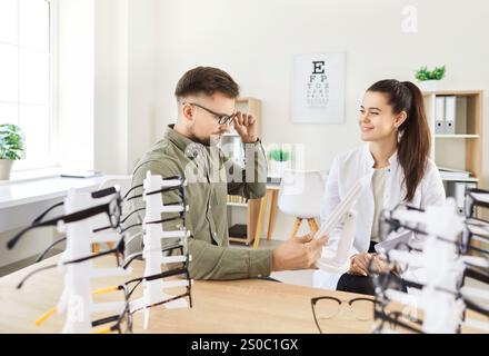 Opticien médecin aide à choisir une nouvelle paire de lunettes à l'homme patient après examen des yeux en clinique Banque D'Images