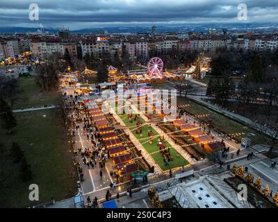 Une vue aérienne captivante du marché de Noël de Sofia au crépuscule, près de NDK, avec des lumières vibrantes, des stands festifs, une grande roue, et les fêtes de fin d'année. Banque D'Images