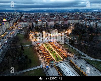 Une vue aérienne captivante du marché de Noël de Sofia au crépuscule, près de NDK, avec des lumières vibrantes, des stands festifs, une grande roue, et les fêtes de fin d'année. Banque D'Images