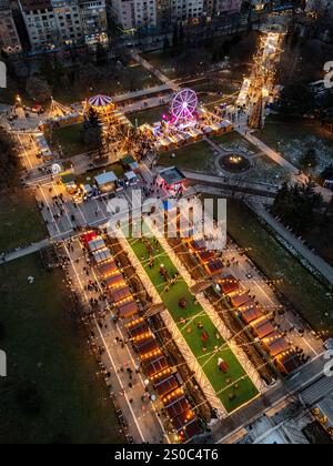 Une vue aérienne captivante du marché de Noël de Sofia au crépuscule, près de NDK, avec des lumières vibrantes, des stands festifs, une grande roue, et les fêtes de fin d'année. Banque D'Images