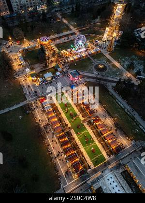 Une vue aérienne captivante du marché de Noël de Sofia au crépuscule, près de NDK, avec des lumières vibrantes, des stands festifs, une grande roue, et les fêtes de fin d'année. Banque D'Images
