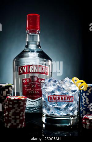Bouteille de vodka Smirnoff et le verre sur une table avec des jetons de poker Banque D'Images