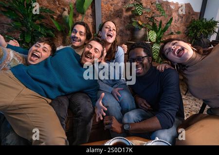 Amical groupe diversifié se lier et rire ensemble dans un café détendu. Banque D'Images