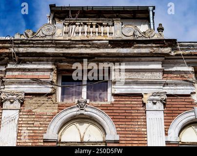 Une vue rapprochée d'une ancienne façade de bâtiment altérée avec des détails architecturaux ornés, y compris des colonnes, des moulures décoratives et un balcon. La str Banque D'Images