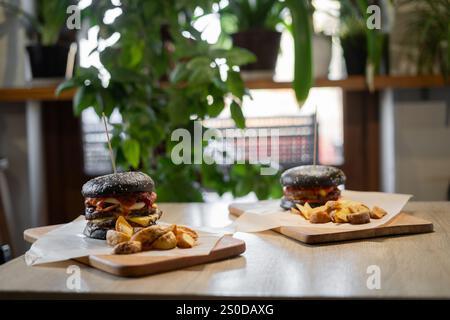 deux hamburgers savoureux et juteux et frites sur table dans le restaurant. Nourriture malsaine et rapide. Copier l'espace Banque D'Images