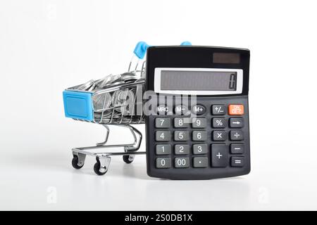 Calculatrice et panier plein de pièces isolées sur fond blanc. Concept de dépenses d'achat Banque D'Images