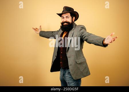 Joyeux cow-boy hipster à l'ancienne en chapeau de cow-boy. Des cowboys américains. Homme barbu dans des styles rétro. Portrait d'homme barbu portant un chapeau de cow-boy. Cow-boys s Banque D'Images