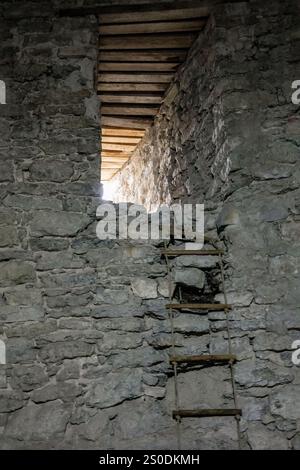 Un mur de pierre avec une échelle menant à lui. L'échelle est rouillée et le mur est recouvert de mousse Banque D'Images