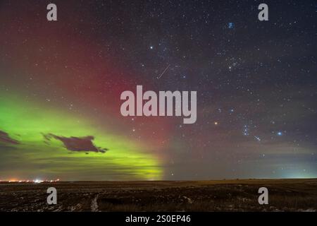 Un météore solitaire du météore Geminid de 2023 au milieu d'une aurore rouge. Banque D'Images