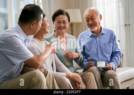 deux couples asiatiques seniors heureux assis sur le canapé à la maison ayant une conversation agréable Banque D'Images