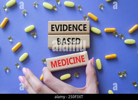 Symbole Evidence Based Medicine. Concept Word Evidence Based Medicine on Wooden Block. Médecin santé. Beau fond violet avec des pilules. Médecine Banque D'Images