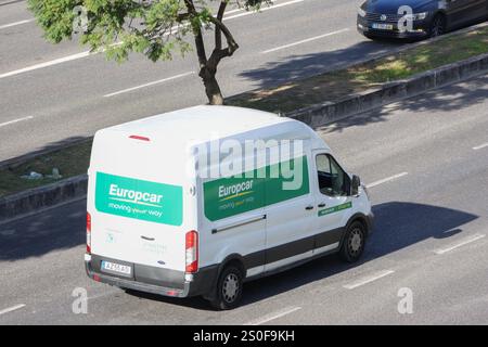 Fourgonnette europcar blanche conduisant sur l'autoroute en milieu urbain, offrant des services de location de voitures et de transport Banque D'Images