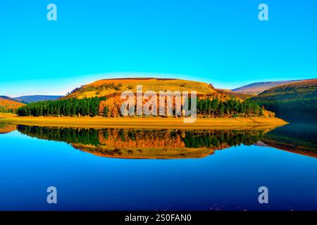 Vue de reflets sur les eaux bleues encore du lac Derwent dans le Peak District par une journée ensoleillée sans nuages. Banque D'Images