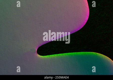 Bords roses et verts sur une forme blanche sur un fond abstrait noir Banque D'Images