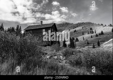 Cabine en bois au milieu d'un paysage montagneux robuste en noir et blanc Banque D'Images
