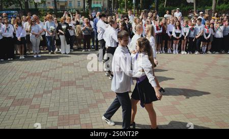 Berezovka, Biélorussie - 31 mai 2024 : des élèves adolescents qui valsent lors de leur dernière journée scolaire dans la cour d'école, tandis que les enseignants et les parents observent et Banque D'Images