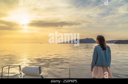 Femme regardant le coucher de soleil serein sur les eaux calmes de l'océan, Santorin, Grèce Banque D'Images