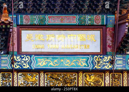 Gros plan du panneau sur l'arche emblématique de l'entrée chinoise dans Chinatown de Manchester, entouré de bâtiments historiques manchester uk Banque D'Images