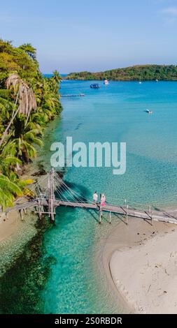 Se promenant le long d'un pont rustique sur une plage immaculée, deux personnes apprécient le paysage côtier à couper le souffle de Koh Kood, en Thaïlande. Verdure luxuriante et t Banque D'Images